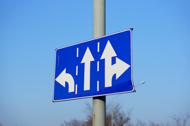 Low angle shot of a blue directions sign with white arrows