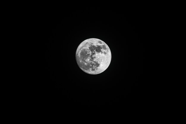 Снимок захватывающей полной луны в ночном небе под низким углом