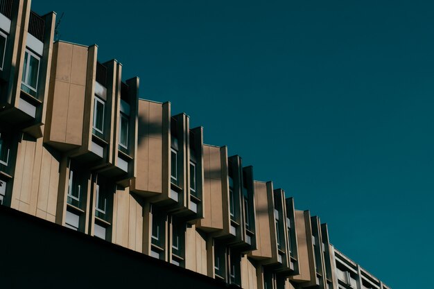 Low angle shot of a brown building with windows and a dark blue sky