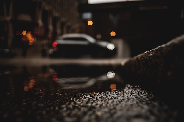 A low angle shot of a car with reflection in the puddle of water