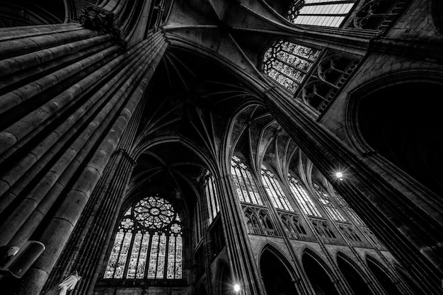 Low angle shot of a cathedral ceiling with windows in black and white