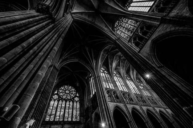 Low angle shot of a cathedral ceiling with windows in black and white