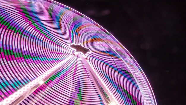 Low angle shot of a colorful amusement park ride taken at night with a pitch