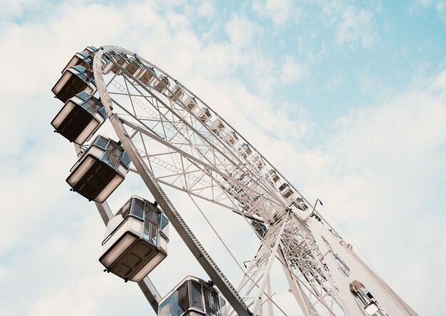 Low angle shot of a Ferris wheel with cloudy blue sky