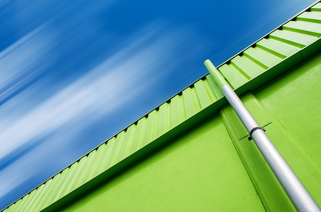 Free photo low angle shot of a green building with a gray pipe under the cloudy sky