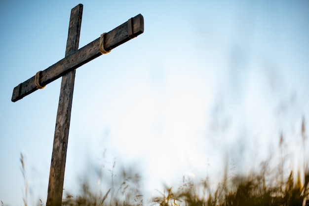 Low angle shot of a handmade wooden cross in a grassy field with a blue