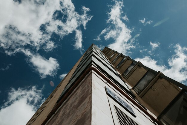 Low angle shot of a high-rise building under a clear blue sky with white clouds