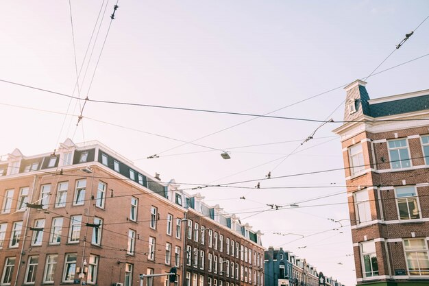 Low angle shot of a lot of electricity wires with brown concrete buildings