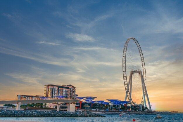 Low angle shot of modern design of a building with a huge Ferris wheel at Bluewaters island in Dubai