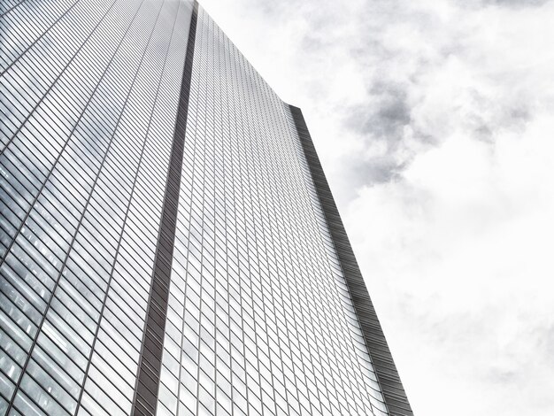Low angle shot of a modern glass skyscraper on a cloudy sky
