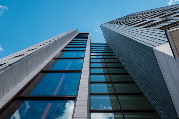 Low angle shot of a modern skyscraper with glass windows and with blue sky