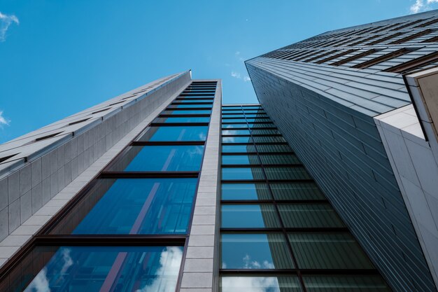 Low angle shot of a modern skyscraper with glass windows and with blue sky