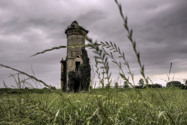 Бесплатное фото Низкий угол выстрела старинного здания посреди поля под мрачным небом