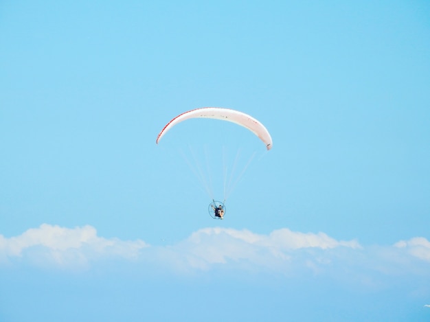 美しい曇り空の下をパラシュートで下る人のローアングルショット