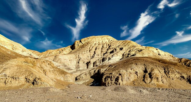 曇った青い空の下、米国カリフォルニア州デスバレーの岩層のローアングルショット