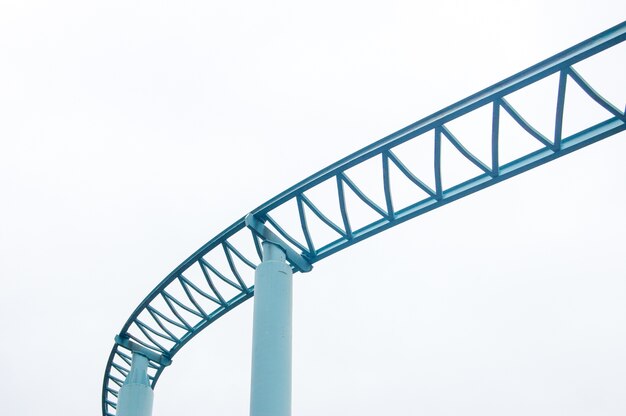 Low angle shot of roller coaster rails isolated on white sky background