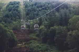 Free photo low angle shot of a ropeway in the middle of a green mountainous scenery