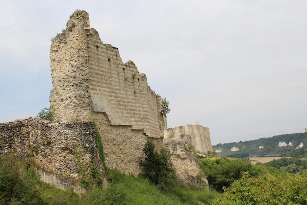Low angle shot of the ruins of a castle in France with the grey sky in the background