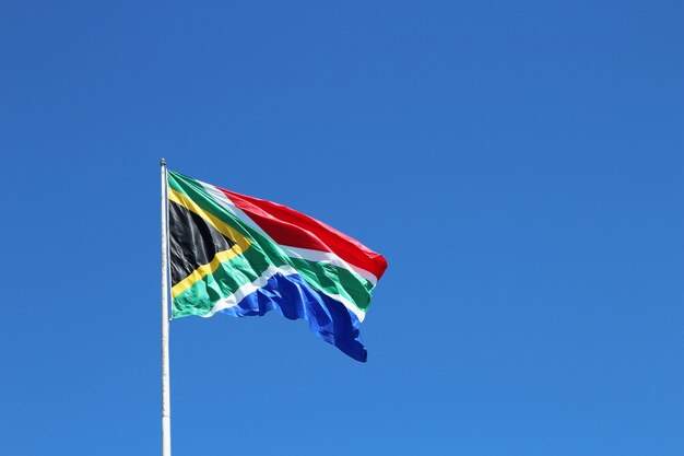 Снимок южноафриканского флага под низким углом на ветру под чистым голубым небом