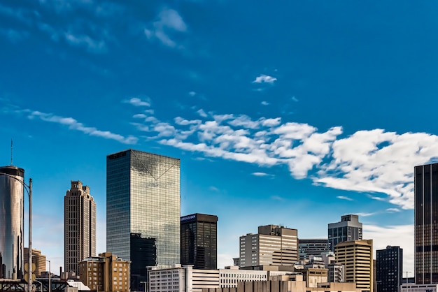 Low angle shot of tall glass buildings under a blue cloudy sky