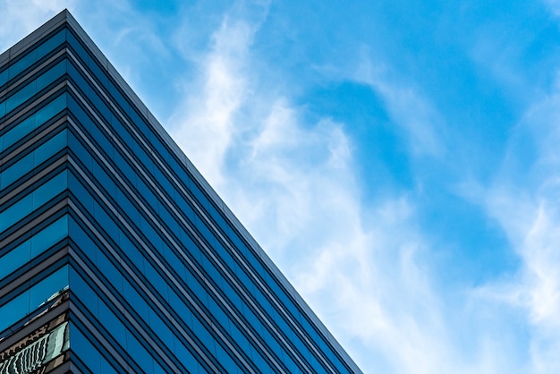 Снимок высоких стеклянных зданий под голубым небом под низким углом