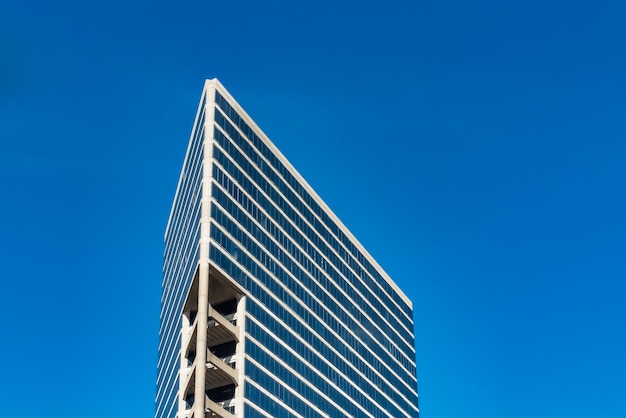 Foto gratuita inquadratura dal basso di edifici di vetro alti sotto un cielo blu nuvoloso