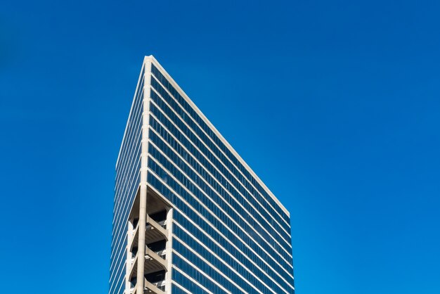 Снимок высоких стеклянных зданий под голубым небом под низким углом
