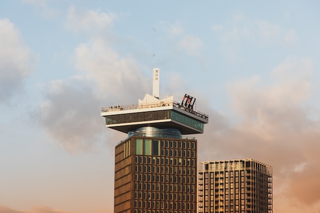 Снимок высокого исторического здания под облачным небом в Амстердаме под низким углом