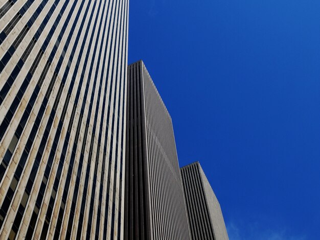 明るく青い空の下で3つの同じ超高層ビルのローアングルショット