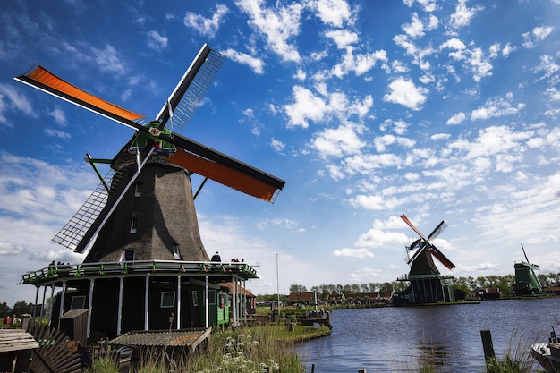 Low angle shot of windmills in Zaanse Schans neighborhood near the lake in  the Netherlands