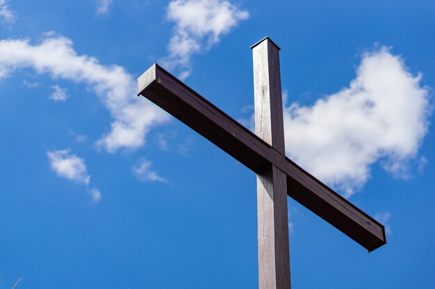 Low angle shot of a wooden cross with a cloudy blue sky