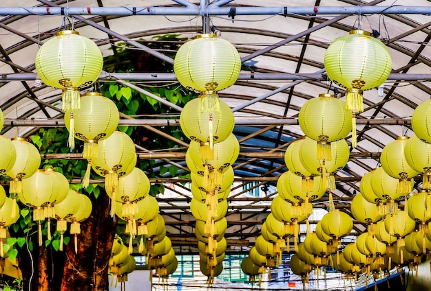 Low angle shot of yellow paper lanterns hung from the metal bars of a ceiling captured in Laos