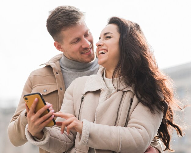 Low angle of smiley couple holding smartphone
