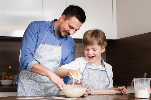 Low angle smiley father and son making dough