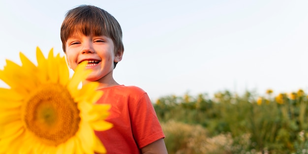 Free photo low angle smiley kid with sunflower
