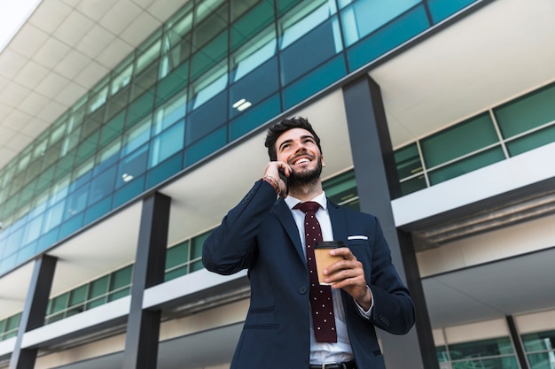 Free photo low angle smiley lawyer with phone and coffee