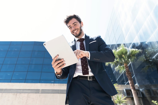 Free photo low angle smiley man with his tablet