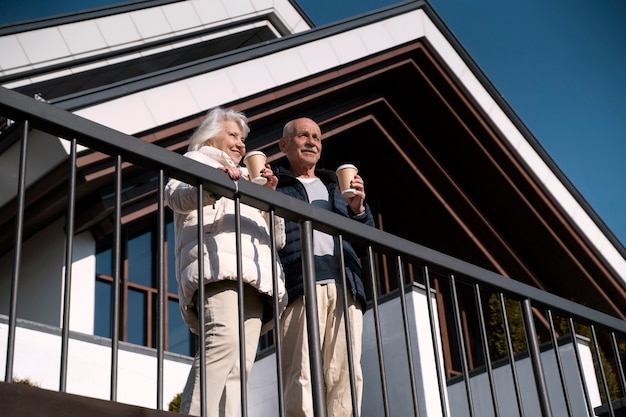 Low angle smiley senior couple with coffee cups