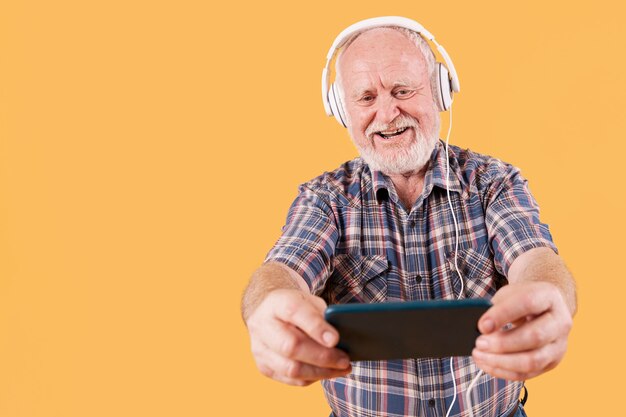 Low angle smiley senior listening music on mobile