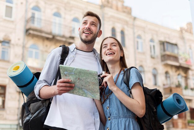 Low angle of smiley tourist couple with map