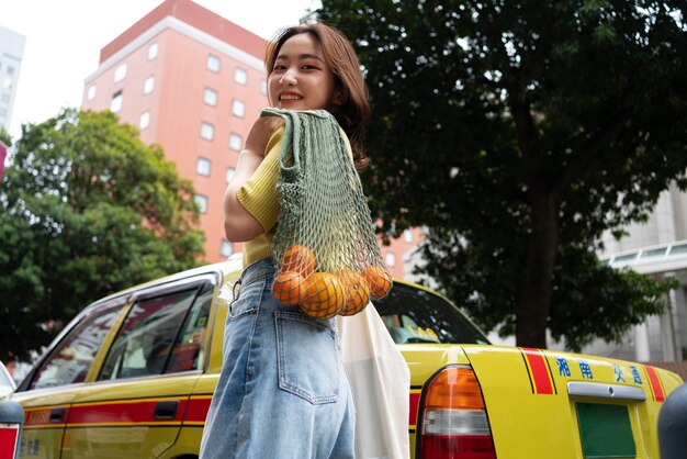 布製バッグを運ぶローアングルスマイリー女性