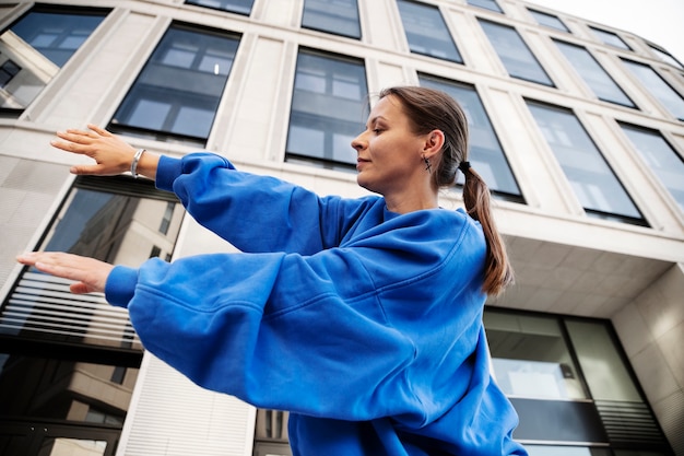 Free photo low angle smiley woman dancing outdoors