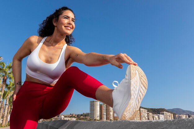 Free photo low angle smiley woman stretching leg