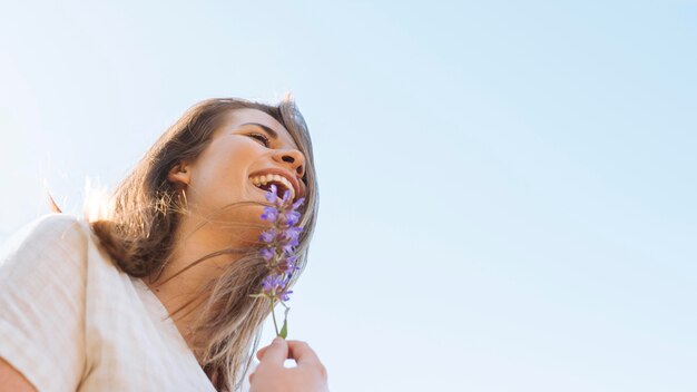 Low angle of smiley woman with flower and copy space