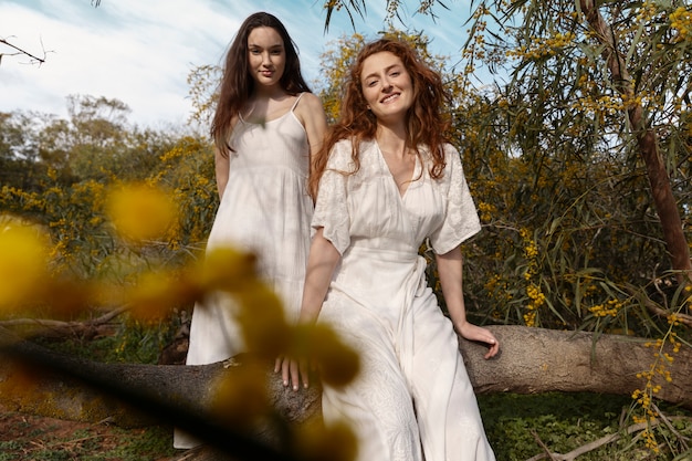 Foto gratuita donne sorridenti di angolo basso che posano all'aperto