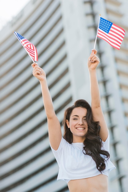 Low angle smiling brunette woman holding two usa flags