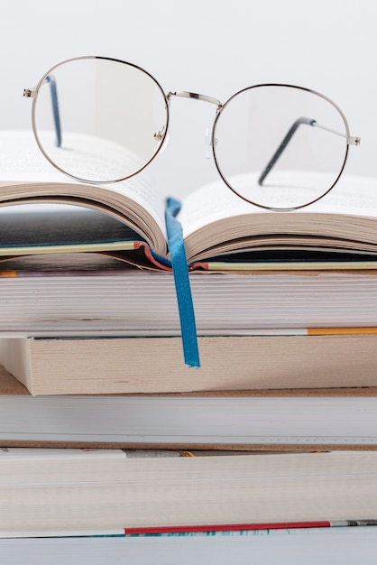 Free photo low angle stack of books with glasses on top