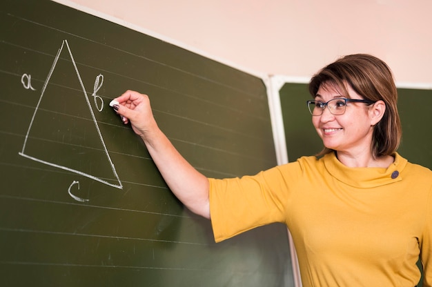 Free photo low angle teacher writing at chalkboard