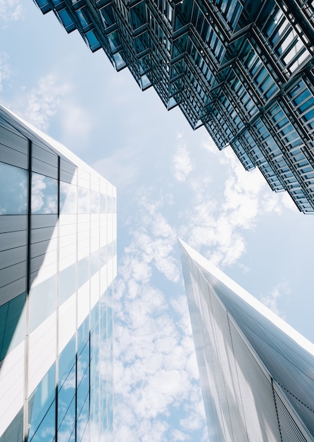 Low angle vertical shot of modern architectural buildings with a cloudy blue sky in the