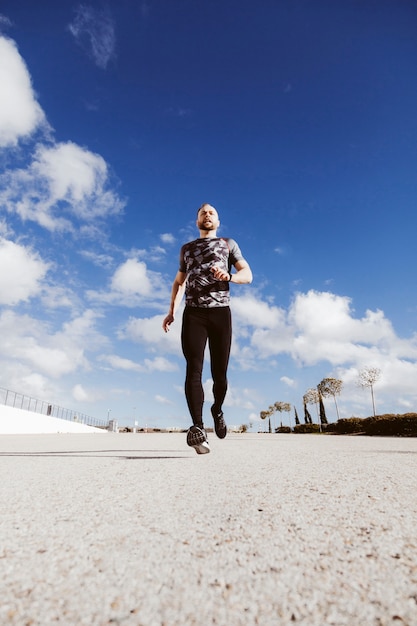 Low angle view of an athletic man running on road